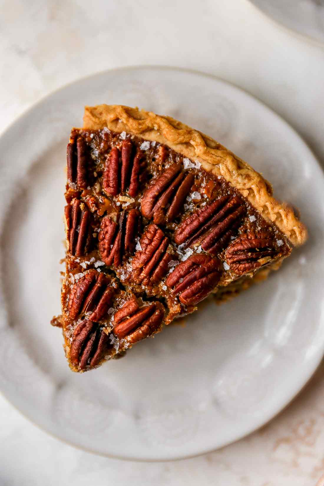 Sea salt bourbon caramel pecan pie slice showing golden filling and toasted pecans on crust
