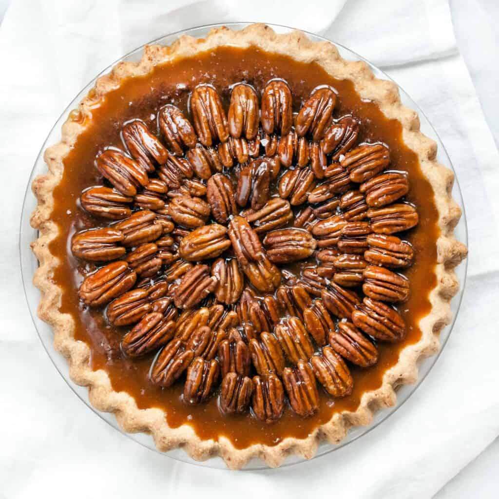 Dark chocolate chunk pecan pie slice with golden caramel filling and toasted pecans on crust