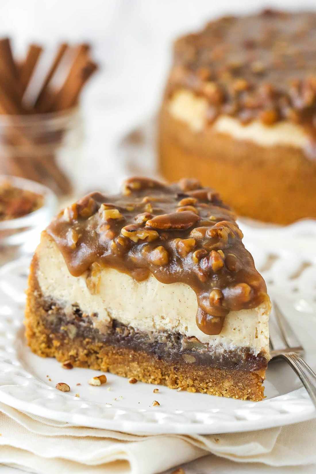 Slice of pecan pie cheesecake with golden caramel filling and toasted pecans on graham crust