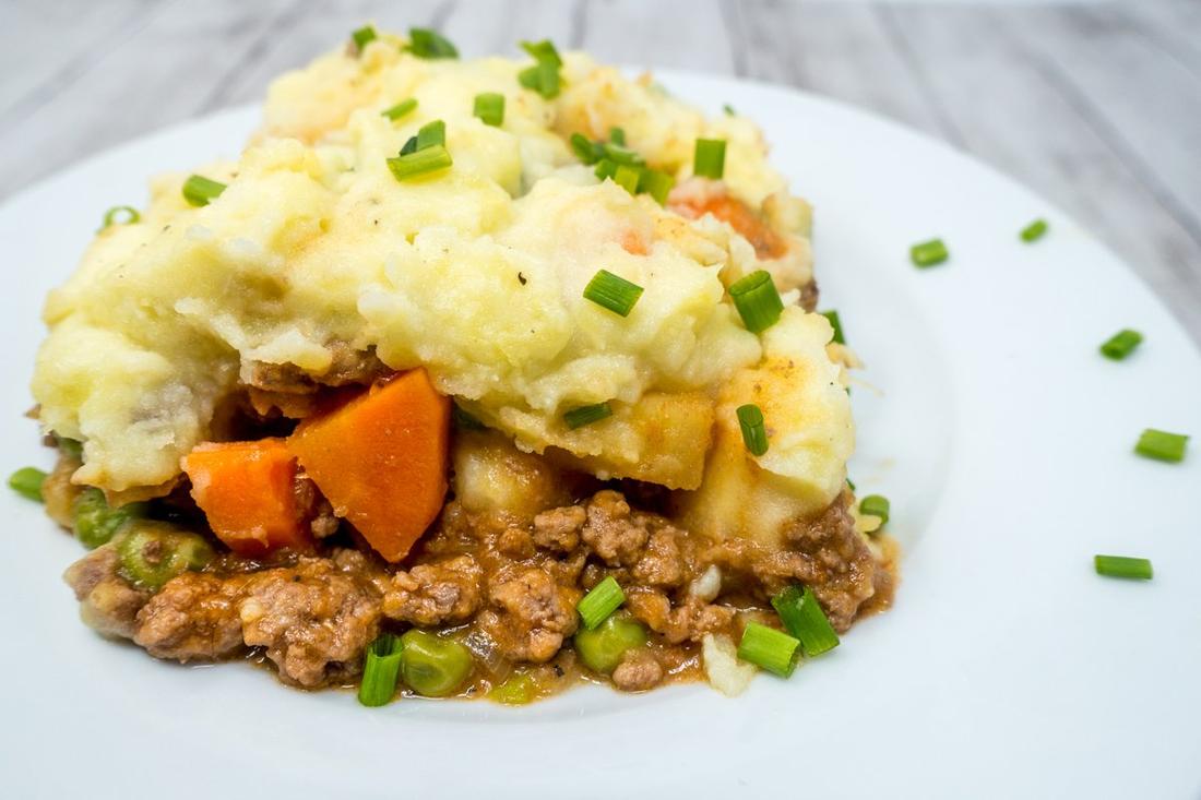 Classic shepherd's pie, cheddar‑strewn mashed topping, savory lamb filling, bubbling cheese, warm casserole dish