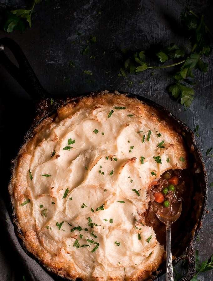 Golden mashed potato‑topped cast‑iron skillet shepherd’s pie with savory beef filling, bubbling cheese, warm casserole