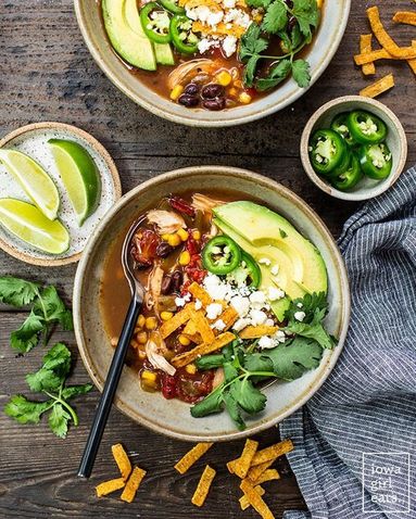 Classic chicken tortilla soup with rich tomato broth, shredded chicken, crunchy tortilla strips, avocado, lime