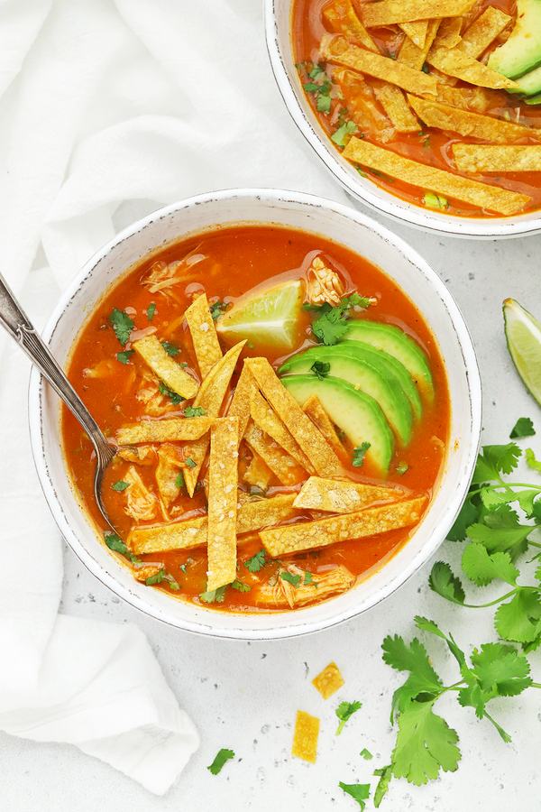 Classic chicken tortilla soup with hearty broth, shredded chicken, crispy tortilla strips, avocado, and lime