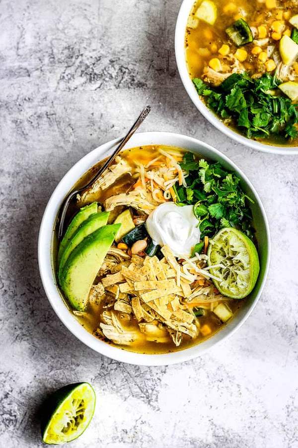 Classic chicken tortilla soup with savory tomato broth, shredded chicken, crunchy tortilla strips, avocado, and lime