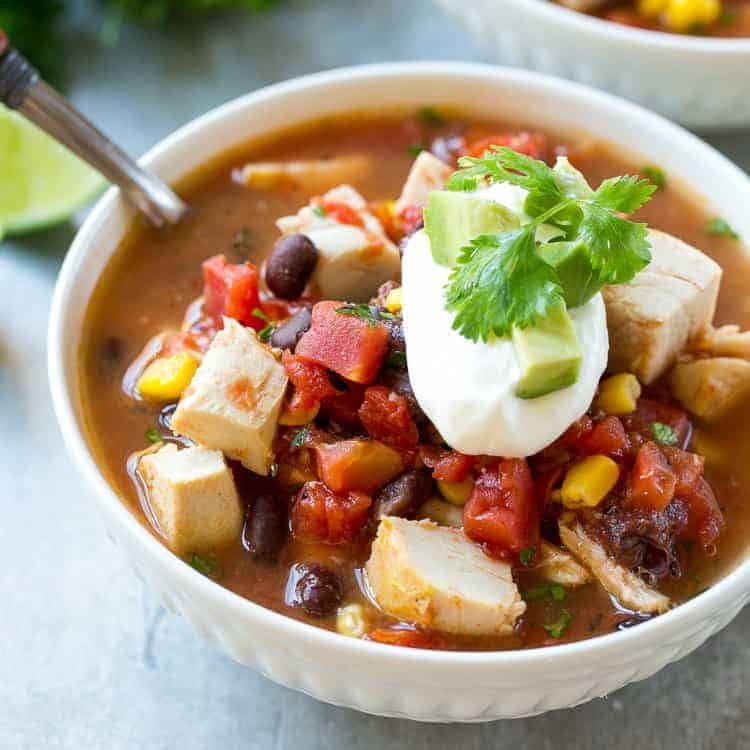 Classic chicken tortilla soup featuring rich tomato broth, shredded chicken, crisp tortilla strips, avocado, and lime