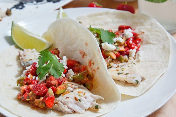 Fish tacos topped with strawberry salsa, cilantro, lime, and crunchy tortilla chips