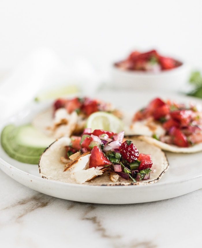 Fish tacos topped with strawberry salsa, lime, cilantro, and a sprinkle of sea salt