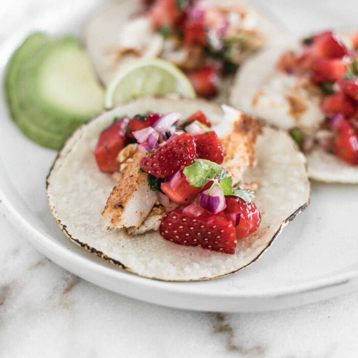 Fish tacos crowned with strawberry salsa, lime, cilantro, and a sprinkle of cotija cheese
