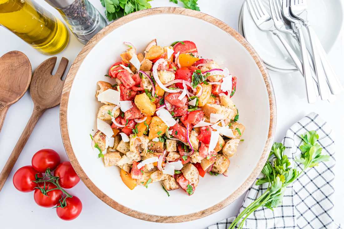 Classic summer panzanella salad with crusty bread cubes, ripe tomatoes, basil, mozzarella, olive oil