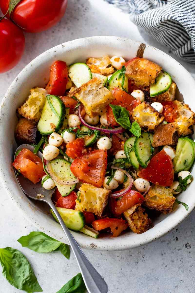 Classic summer panzanella salad featuring crusty bread cubes, ripe tomatoes, basil, mozzarella, olive oil