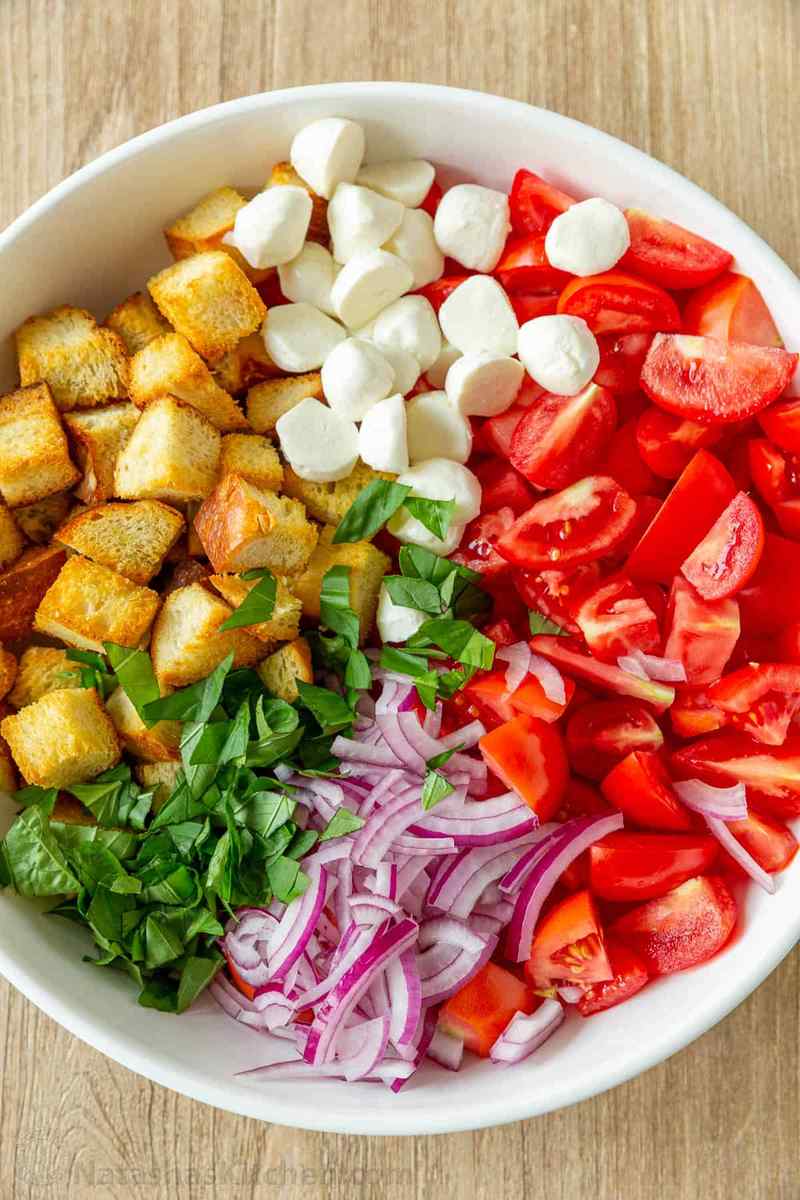 Classic summer panzanella salad with crusty bread cubes, ripe tomatoes, basil, mozzarella, olive oil