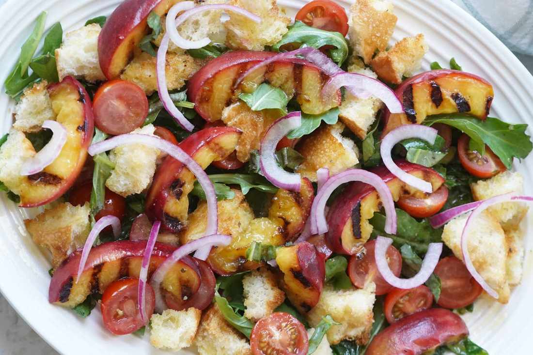 Peach & mozzarella panzanella with crispy Tuscan bread, ripe tomatoes, basil, and creamy mozzarella in a citrusy vinaigrette