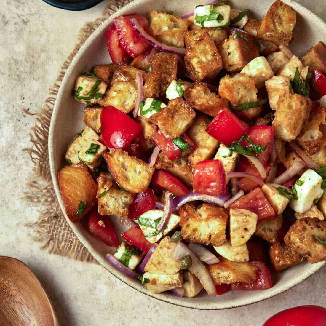 Classic summer panzanella with crusty bread cubes, ripe tomatoes, basil, mozzarella, and olive oil